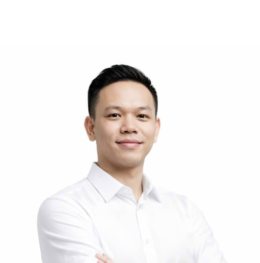 Về chúng tôi 34 Người đàn ông trẻ tuổi, tự tin, mặc áo sơ mi trắng, đứng trước nền trắng, thể hiện sự chuyên nghiệp.